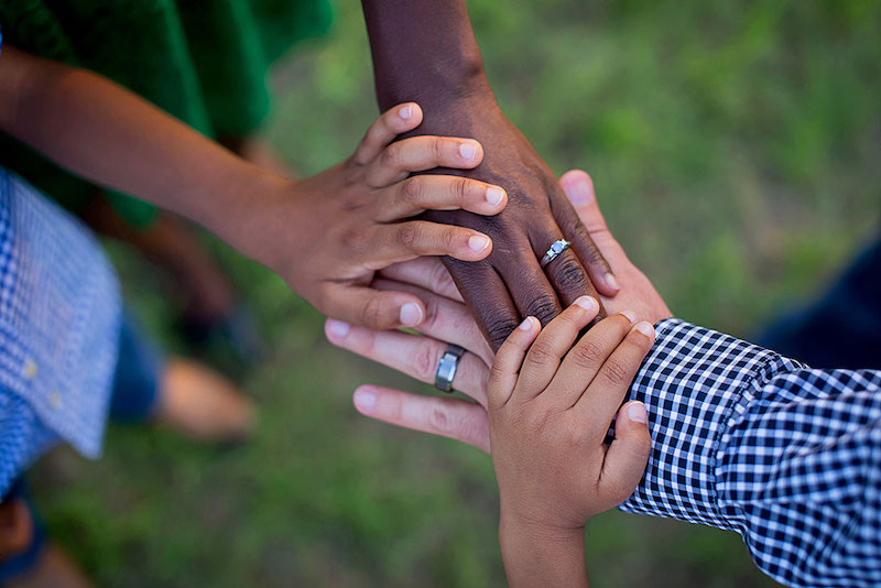 Community members placing their hands together